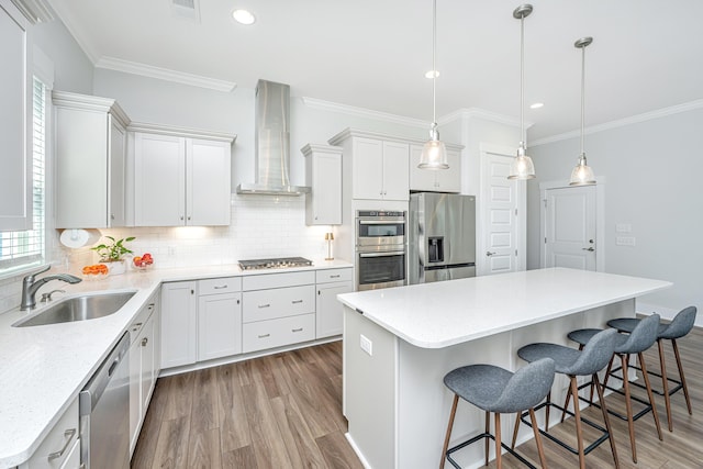 kitchen featuring wall chimney exhaust hood, stainless steel appliances, light wood-style floors, decorative backsplash, and ornamental molding