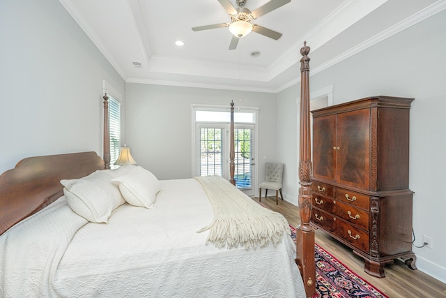 bedroom with a raised ceiling, visible vents, light wood finished floors, and baseboards
