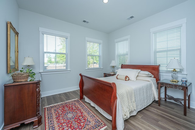 bedroom featuring baseboards, wood finished floors, and visible vents