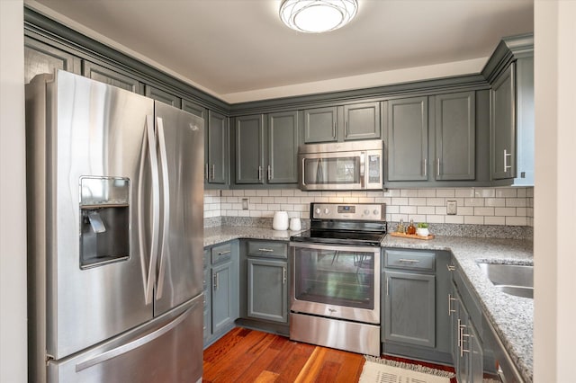 kitchen with gray cabinetry, sink, tasteful backsplash, dark hardwood / wood-style floors, and appliances with stainless steel finishes