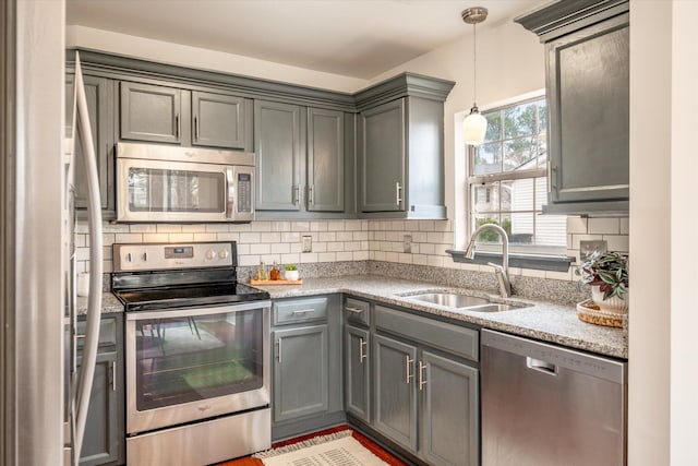 kitchen with gray cabinetry, backsplash, hanging light fixtures, sink, and appliances with stainless steel finishes