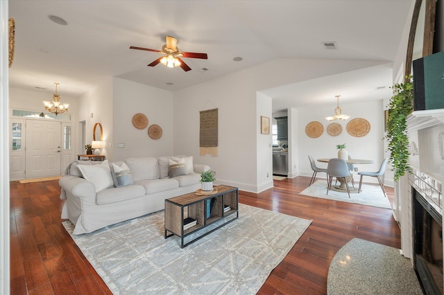 living room with vaulted ceiling, ceiling fan with notable chandelier, and dark hardwood / wood-style floors