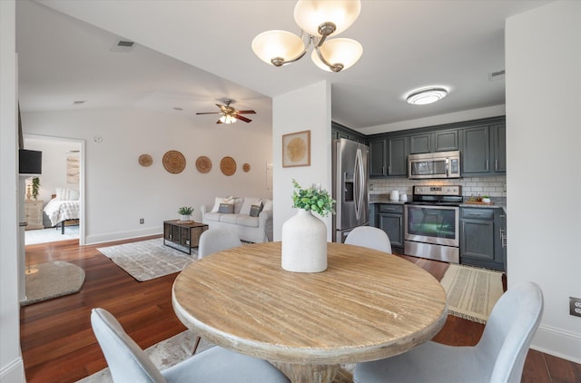 dining area featuring ceiling fan with notable chandelier, dark hardwood / wood-style floors, and lofted ceiling