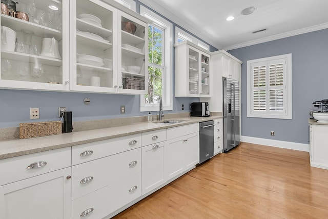 7021 Schooner St, Charleston, SC 29492 - kitchen with appliances with stainless steel finishes, crown molding, glass insert cabinets, white cabinetry, and light countertops