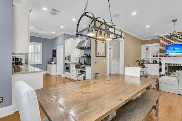 7021 Schooner St, Charleston, SC 29492 - dining area with ornamental molding, light wood finished floors, recessed lighting, a ceiling fan, and a fireplace