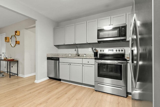120 Lisa Dr, Summerville, SC 29485 - kitchen with light wood finished floors, stainless steel appliances, a sink, baseboards, and light stone counters