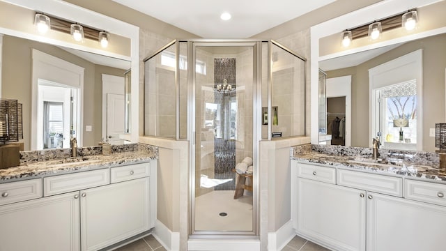 bathroom with a shower with shower door, tile patterned floors, and double sink vanity