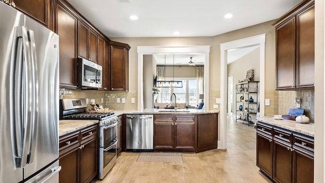 kitchen with sink, appliances with stainless steel finishes, light hardwood / wood-style flooring, and decorative backsplash