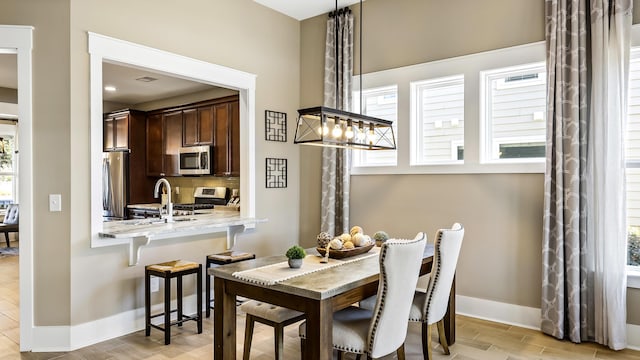 dining area with light hardwood / wood-style floors, sink, and a healthy amount of sunlight