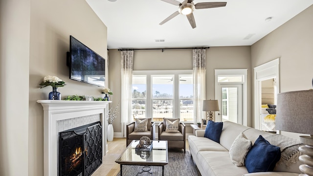 living room with a tiled fireplace, ceiling fan, and hardwood / wood-style floors