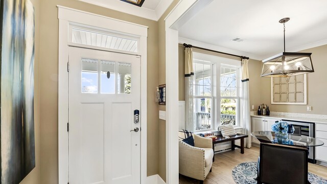 foyer with light hardwood / wood-style floors, a notable chandelier, and ornamental molding