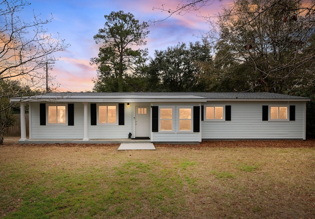 view of front of property featuring covered porch and a yard