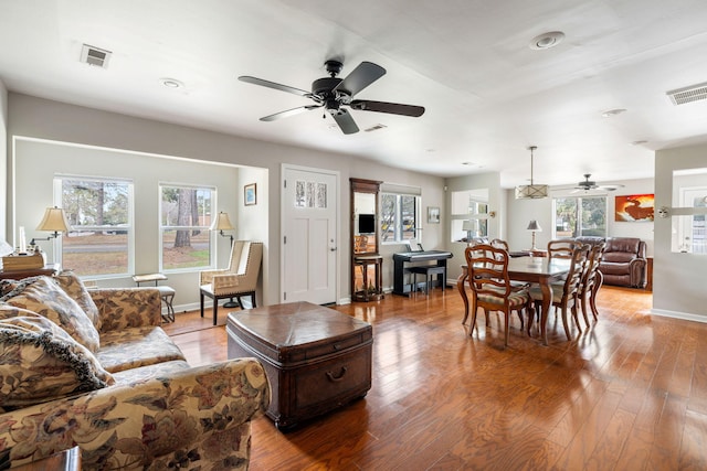 living room with light wood-type flooring, visible vents, and baseboards