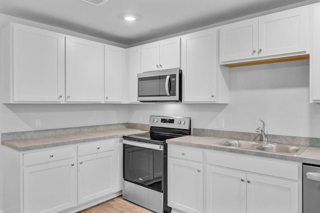 407 Spruce Ivy St, Moncks Corner, SC 29461 - kitchen featuring stainless steel appliances, a sink, white cabinetry, light countertops, and light wood-style floors