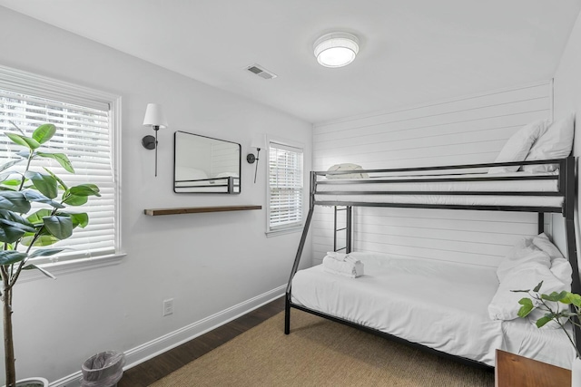 bedroom with multiple windows and dark wood-type flooring