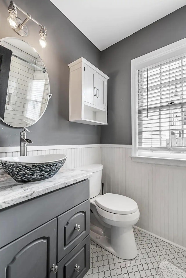 bathroom with vanity, tile patterned floors, toilet, and wood walls