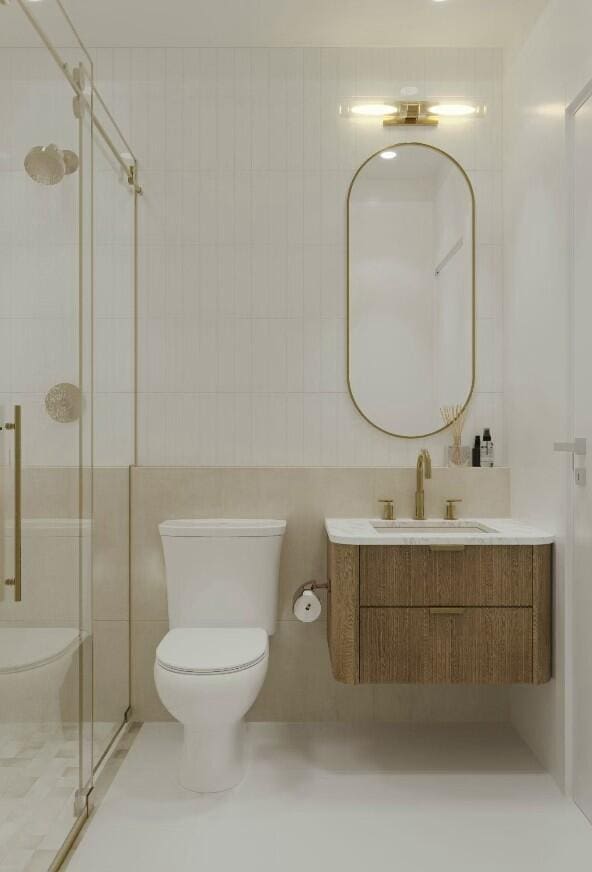 bathroom featuring a shower with door, vanity, tile walls, and toilet