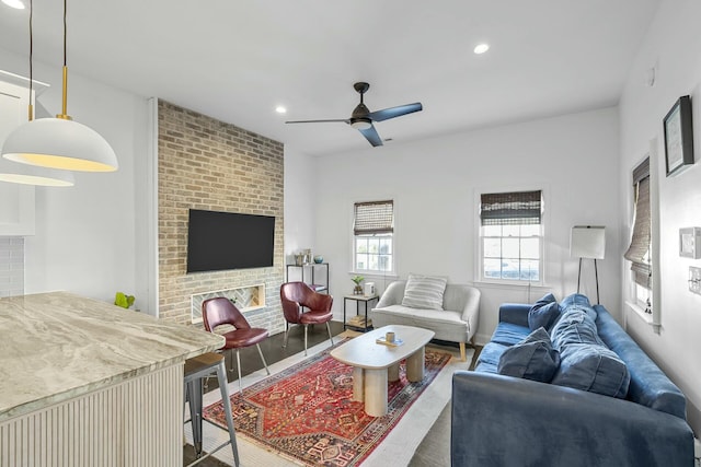 living room with hardwood / wood-style flooring, ceiling fan, and a brick fireplace