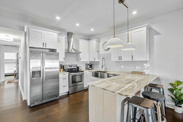 kitchen with wall chimney exhaust hood, sink, white cabinetry, appliances with stainless steel finishes, and pendant lighting