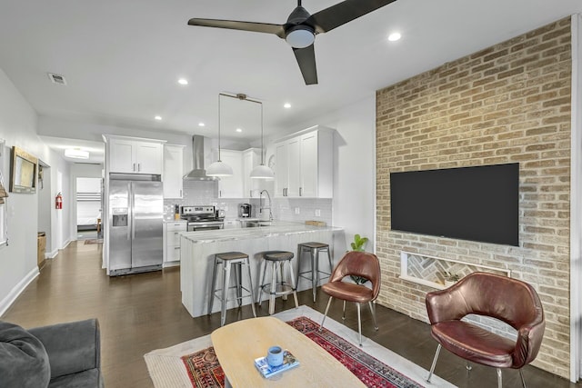 living room with dark hardwood / wood-style flooring, sink, ceiling fan, and brick wall