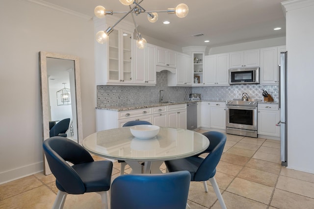 kitchen with backsplash, decorative light fixtures, stainless steel appliances, and white cabinets