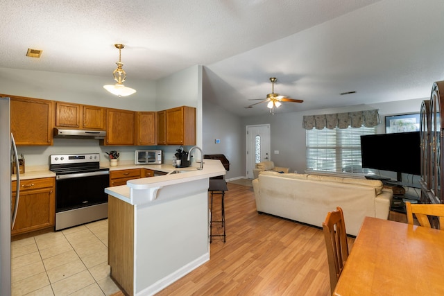 3347 Walter Dr, Johns Island, SC 29455 - kitchen featuring stainless steel appliances, vaulted ceiling, under cabinet range hood, open floor plan, and brown cabinets