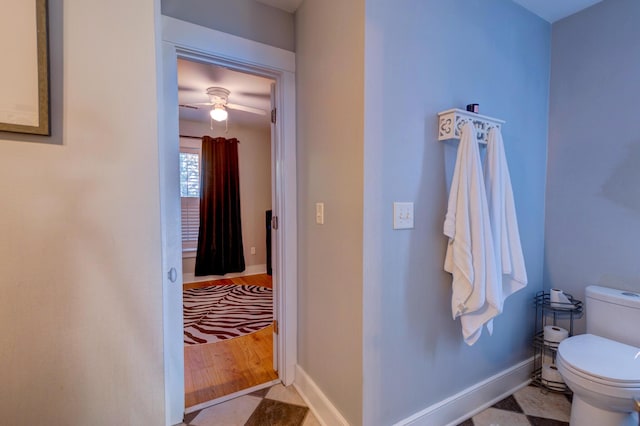 half bath with baseboards, ceiling fan, and toilet