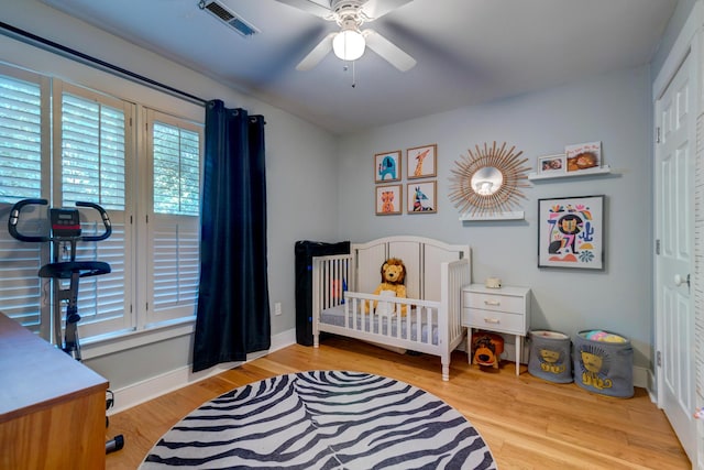 bedroom with a closet, visible vents, a ceiling fan, wood finished floors, and baseboards