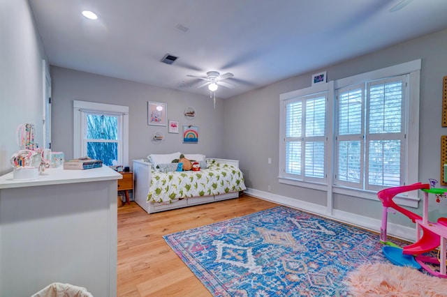 bedroom featuring ceiling fan, light wood-style flooring, visible vents, and baseboards