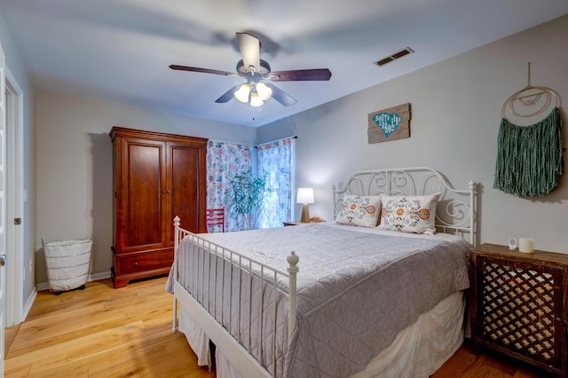 bedroom featuring baseboards, visible vents, ceiling fan, and light wood finished floors