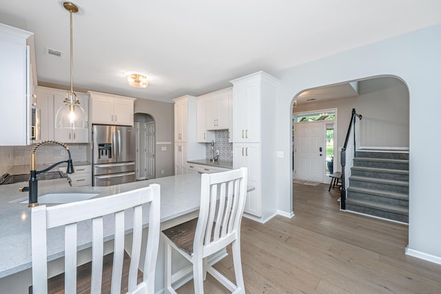 468 Maple Oak Ln, Charleston, SC 29414 - kitchen featuring stainless steel fridge, arched walkways, decorative backsplash, and light wood-style floors