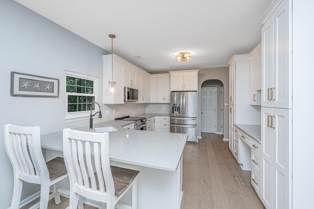 468 Maple Oak Ln, Charleston, SC 29414 - kitchen featuring stainless steel appliances, a peninsula, white cabinetry, light stone counters, and light wood-style flooring