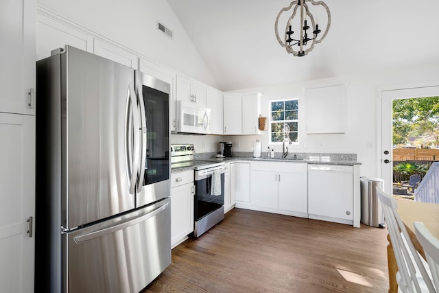 kitchen featuring stainless steel appliances, visible vents, dark wood-type flooring, vaulted ceiling, and a sink