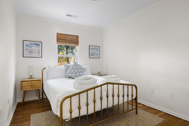 bedroom featuring baseboards, crown molding, visible vents, and wood finished floors