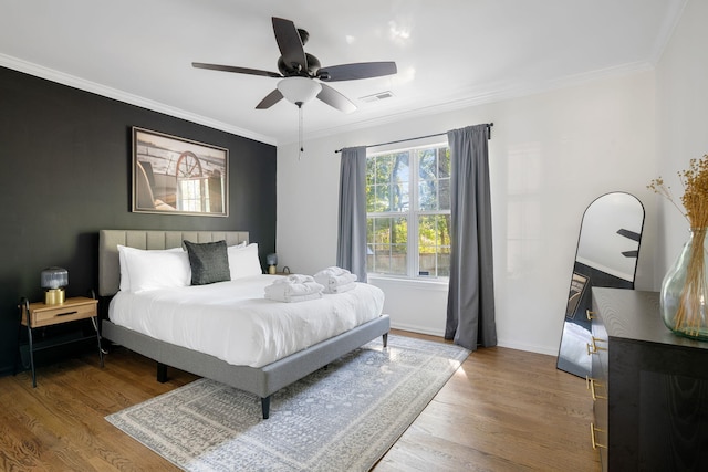 bedroom with visible vents, wood finished floors, and ornamental molding