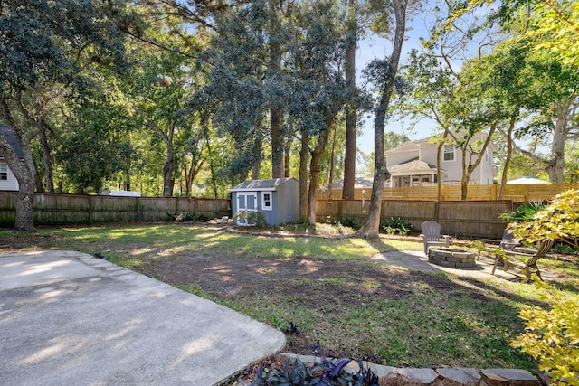 view of yard featuring an outdoor fire pit, a patio area, a fenced backyard, and an outdoor structure