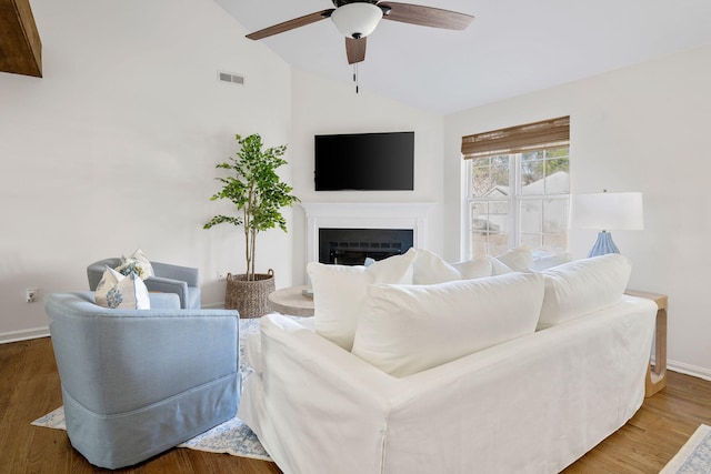 living room featuring visible vents, a ceiling fan, wood finished floors, vaulted ceiling, and a fireplace