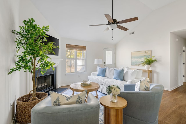 living room featuring ceiling fan, a fireplace, wood finished floors, visible vents, and baseboards