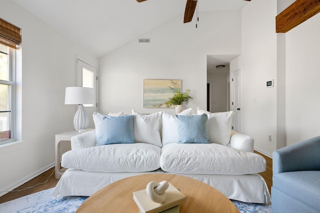 living area with baseboards, visible vents, ceiling fan, beamed ceiling, and high vaulted ceiling