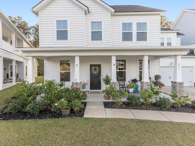 view of front of property featuring a porch, concrete driveway, and a garage