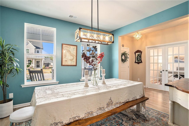 dining space featuring french doors, baseboards, visible vents, and wood finished floors