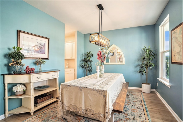 dining space with an inviting chandelier, baseboards, and wood finished floors