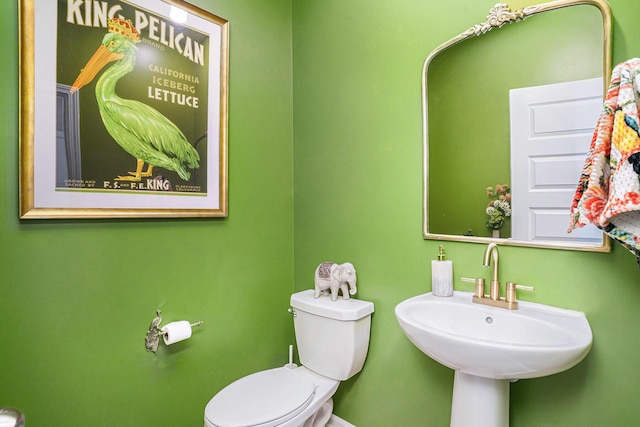 half bath featuring toilet, baseboards, and a sink