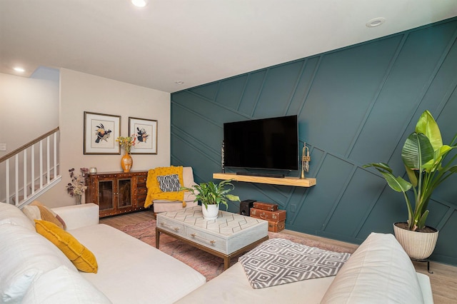 living room featuring recessed lighting, wood finished floors, stairs, and a decorative wall