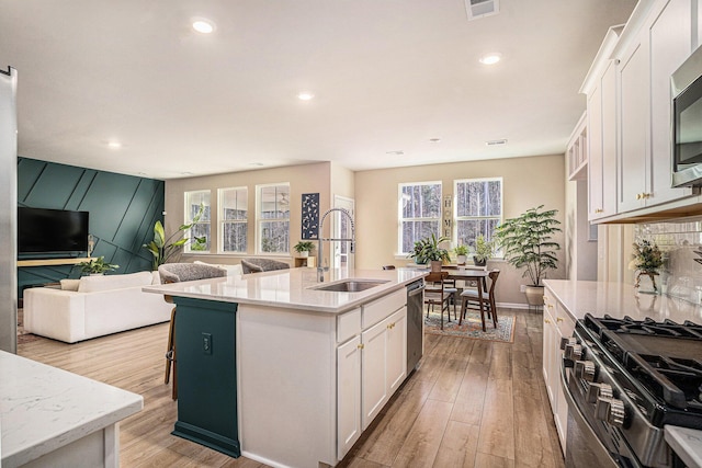 kitchen with light wood-style flooring, white cabinets, appliances with stainless steel finishes, and a sink