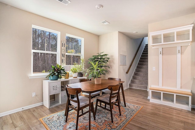 dining space with stairway, visible vents, light wood-type flooring, and baseboards