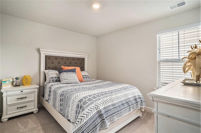 bedroom featuring visible vents, light colored carpet, and baseboards