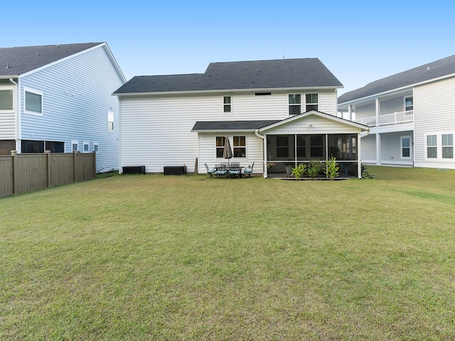 rear view of house with a lawn, a shingled roof, and a sunroom