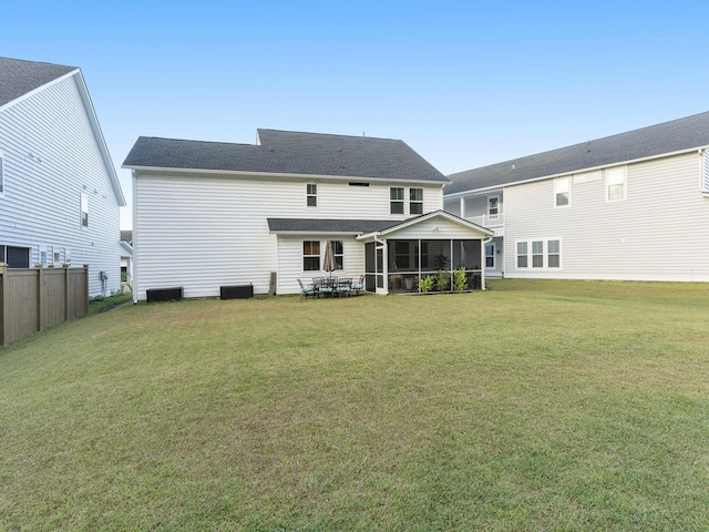 back of house featuring a lawn, fence, a sunroom, and roof with shingles