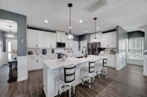 kitchen featuring visible vents, freestanding refrigerator, a sink, light countertops, and a kitchen breakfast bar